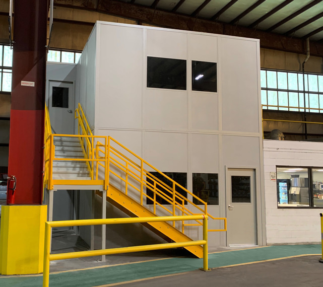 Two-story grey modular office with switchback stairs for entry to both floors from plant floor